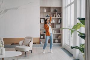 Girl having fun crazy in her living room. Relaxation and dancing at home, emotional expressions. photo