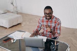 un chico afroamericano feliz tiene una conversación en línea. aprendizaje a distancia, revisión de tareas.