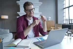 German young male entrepreneur in glasses having pleasant online conversation with colleagues photo