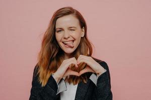 Happy excited young woman showing heart shape sign photo