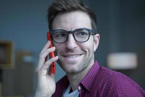 Close up photo of young handsome cheerful german man in glasses making phone call