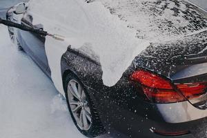 Car in white soap suds during professional auto cleaning outdoor photo