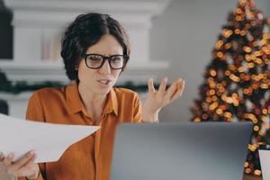 Stressed Italian businesswoman feels angry with error or mistake while remotely working on Christmas photo