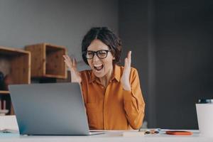 Mad Italian businesswoman shouting in distress from hopelessness while working online on laptop photo