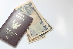 yen, dólar, baht y pasaporte sobre fondo blanco foto