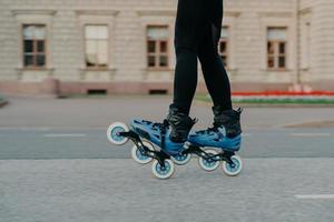 Cropped shot of faceless woman wears rollerblades for riding on road enjoys hobby in fresh air has active lifestyle tries new rollers after purchasing. People hobby and outdoor free time activities photo