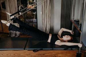 Young woman working hard on pilates reformer photo