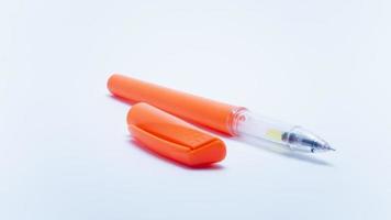 Photo of a bright orange ballpoint pen on a white background. Suitable for design elements of education, office stationery, and student study supplies.