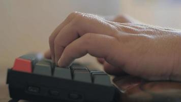 el hombre está escribiendo en el teclado. teclado gris con botón naranja video