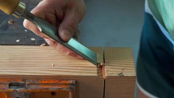 een schrijnwerker snijdt een profiel van een been uit hout met een beitel video