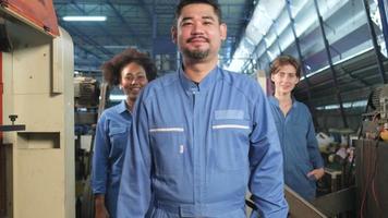Multiracial industry workers collaborate with unity and express happiness. Male leader turns back and team arms crossed together with smiles and cheerful in factory, professional engineer occupation.