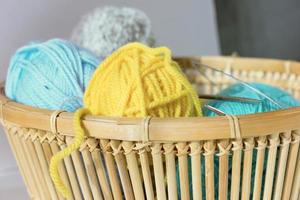 colorful balls of wool yarn and knitting needles in a wicker basket photo