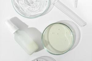 top view of cosmetic fluid in glass bottle and petri dish and test tube on a laboratory table. lab research on skin care cosmetic ingredients and product safety. photo