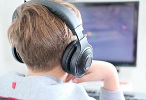 teenager boy wearing earphones looking at computer monitor. photo