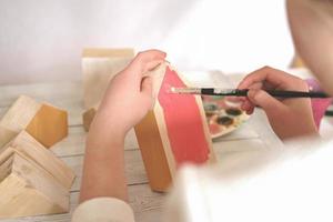 teenager girl's hands painting wooden toy house in red. hobby or leisure during quarantine. photo