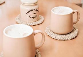 tazas de café en posavasos de yute en una mesa. accesorios de cocina tejidos a mano. decoración natural del hogar. foto