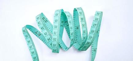 Old wrinkled green rubber tape measure with negative space. Rubber tape measure isolated on the gray white background. Useful for sewing cloth or fabric. photo