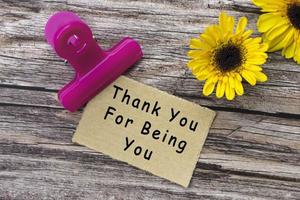 Thank you for being you text on torn paper with clip holder on wooden surface. photo