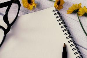 Note book flat lay with sunflowers on wooden desk. Directly above. photo