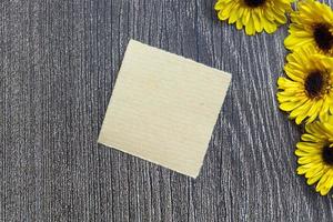 Torn brown paper on wooden surface and sunflower flat lay with copy space. photo