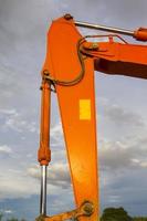 Excavators are stationary after work in the evening, using the arms of the car as a frame to see the beautiful sky and clouds of various colors in the evening, a beam of light into the beautiful river photo