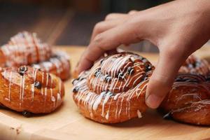 close up hand pick cinnamon danish roll on table photo