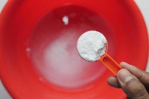 Washing powder in plastic spoon top view photo