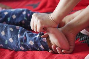mother giving a foot therapy to her child on bed , photo