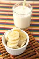 vaso de leche y plátano en la mesa por la mañana foto