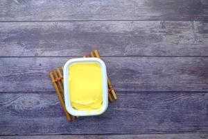 fresh butter in a container on wooden table top view photo