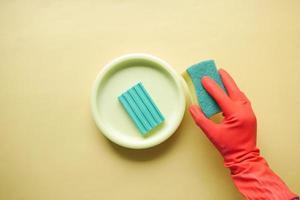 sponge , rubber gloves and colorful plate on blue photo