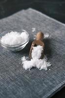 Coarse salt in wooden spoon on table photo