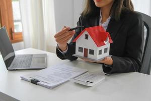 Accountant, businessman, real estate agent, business woman handing model house to customers along with house interest calculation documents for customers to sign. photo