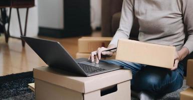 los pequeños empresarios inician un negocio en el hogar organizando productos con cajas de paquetes marrones, ideas de inicio de pequeños negocios en el hogar. foto