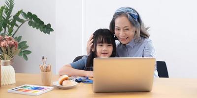 Asian grandmather teach granddaughter drawing and doing homework at home. photo