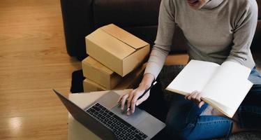 Starting small businesses SME owners female entrepreneurs Write the address on receipt box and check online orders to prepare to pack the boxes, sell to customers, sme business ideas online. photo