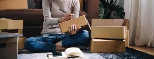Starting small businesses SME owners female entrepreneurs Write the address on receipt box and check online orders to prepare to pack the boxes, sell to customers, sme business ideas online. photo