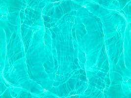 Defocus blurred transparent blue colored clear calm water surface texture with splashes and bubbles. Trendy abstract nature background. Water waves in sunlight. Blue water background. photo