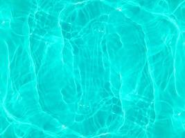 Defocus blurred transparent blue colored clear calm water surface texture with splashes and bubbles. Trendy abstract nature background. Water waves in sunlight. Blue water background. photo