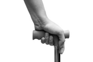 Closeup of hand holding a walking stick or a cane, isolated on white background. Medical and healthcare concept. Black and White tone photo