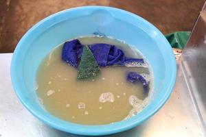 Dust cloths and detergents are in plastic sky blue bowl on stainless table. photo