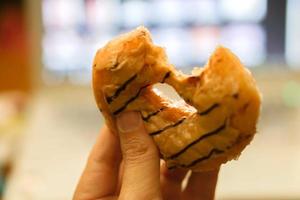 Hand holding peanut butter doughnut was eaten on blurry window background. photo