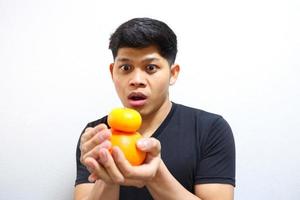 Attractive asian man eating oranges. Isolated on white background photo