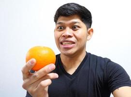 atractivo hombre asiático comiendo naranjas. aislado sobre fondo blanco foto
