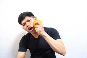 atractivo hombre asiático comiendo naranjas. aislado sobre fondo blanco foto