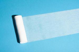 Sterile bandage roll unwound on blue background. photo