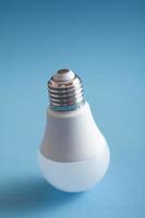 White light bulb standing on blue background. photo