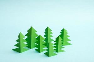 Green paper trees on blue background. Origami forest, photo