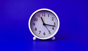 white alarm clock set on a blue background time concept and waking up photo