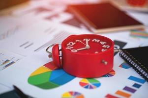 planificador de trabajo con reloj rojo en el escritorio con gráfico de gráfico de negocios. foto